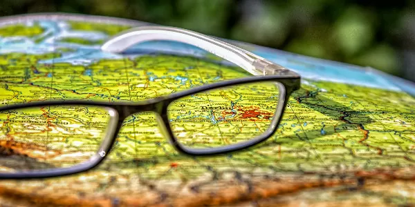 reading glasses on a map representing someone comparing international insurance companies