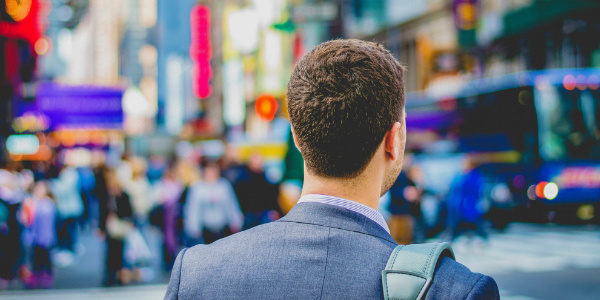 Male Millennial in a suit searches through a crowded street