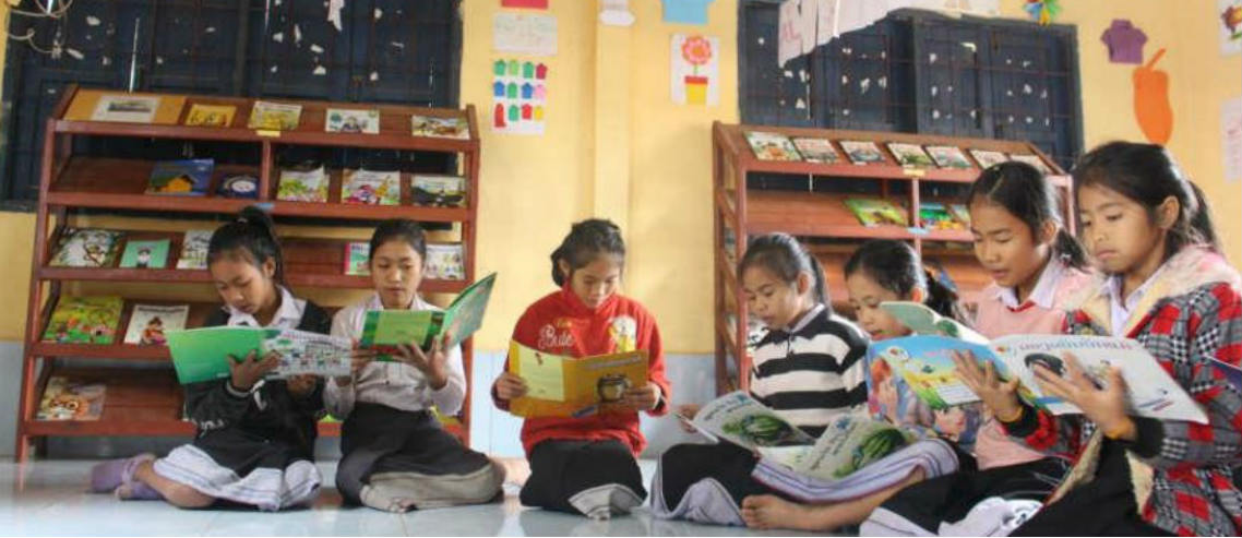 young girls from laos read books in a library built by a partnership between room to read and pacific prime