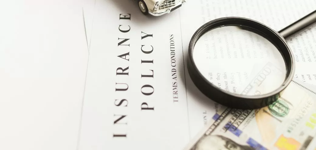 A magnifying glass laying on a paper with the words insurance policy on it