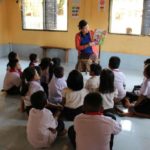 a teacher reads to a classroom of young students in a room to read and pacific prime built school in laos