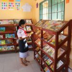 a young woman checks out the book selection in a library room to read and pacific prime built in laos