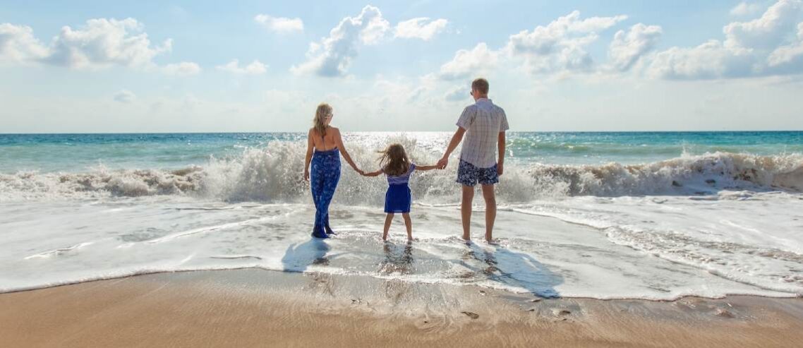 Family holding hands standing in the water by the ocean