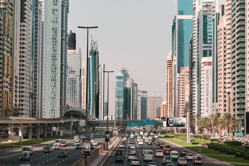 Cars On Dubai Streets With Tall Buildings By Day