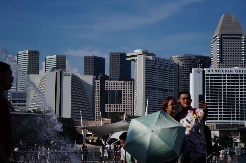 Couple At Merlion Park, Singapore: Maternity Insurance And Cherished Memories