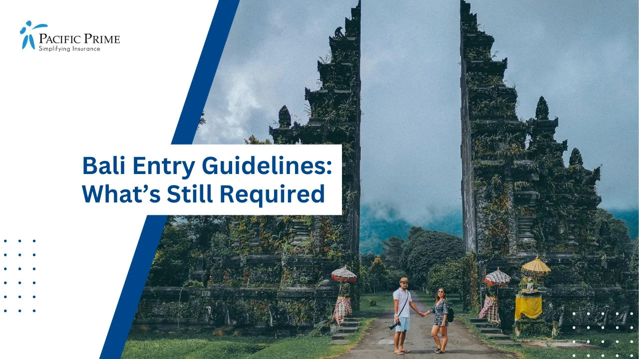 Image of Couple Standing At Bali Handara Gate Between Traditional Black Stone Statues with text overlay of "Bali Entry Guidelines: What’s Still Required"