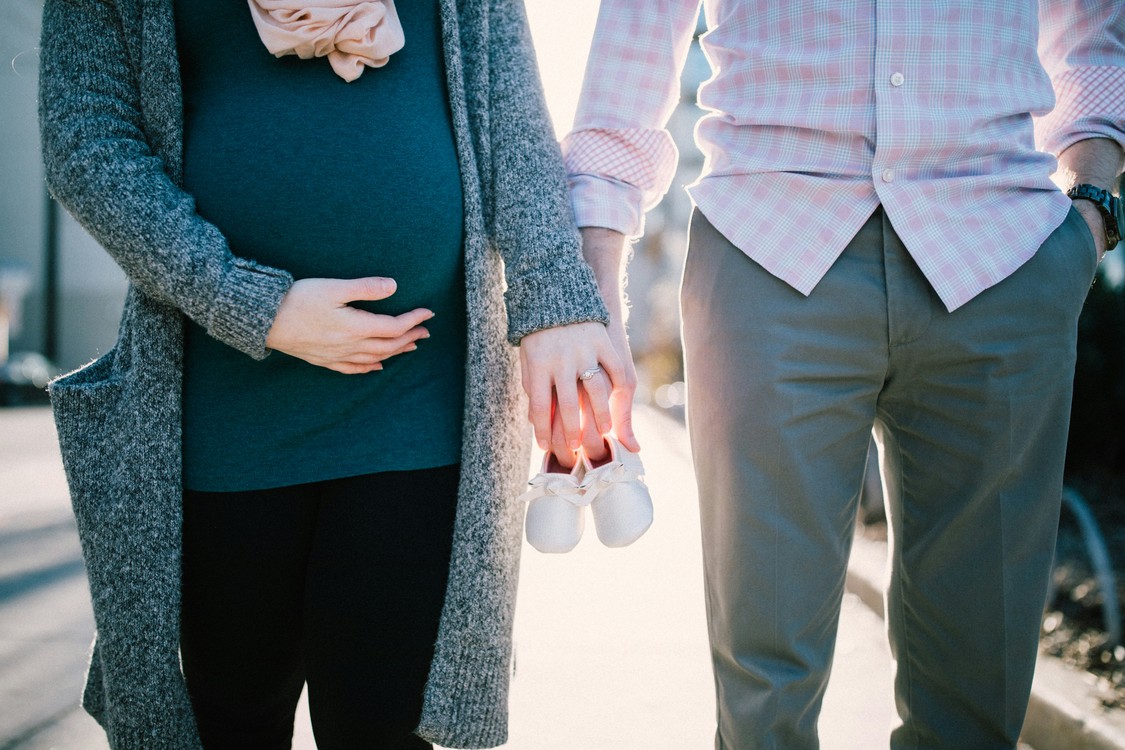 Man and Pregnant Woman With Baby Shoes In Daytime