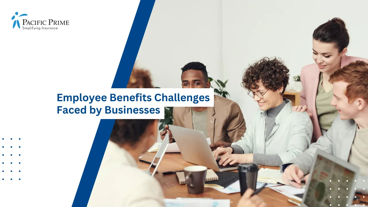 Image of Multicultural Team Collaborating At Table With Laptops In Office Meeting with text overlay of "Employee Benefits Challenges Faced by Businesses"
