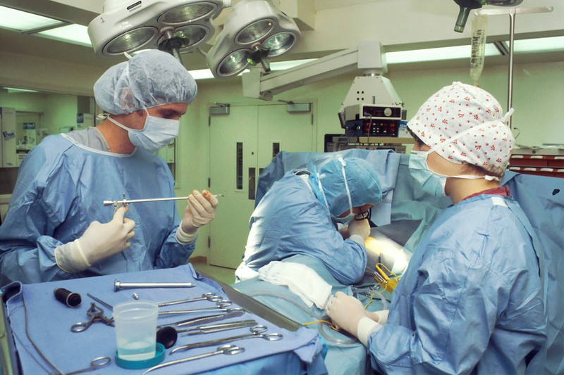 Two Surgeons And Nurse In Surgery On Patient