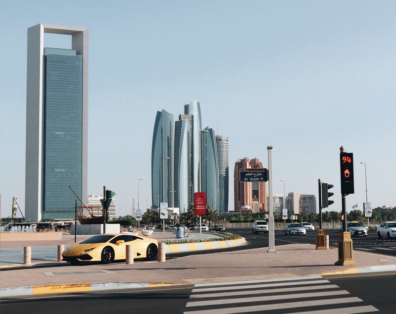 Yellow car cruising by Abu Dhabi building, UAE